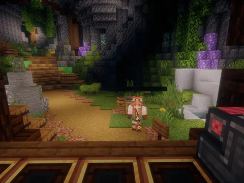 A cozy cave-interior build with plants, a waterfall, and a player standing on a wooden path